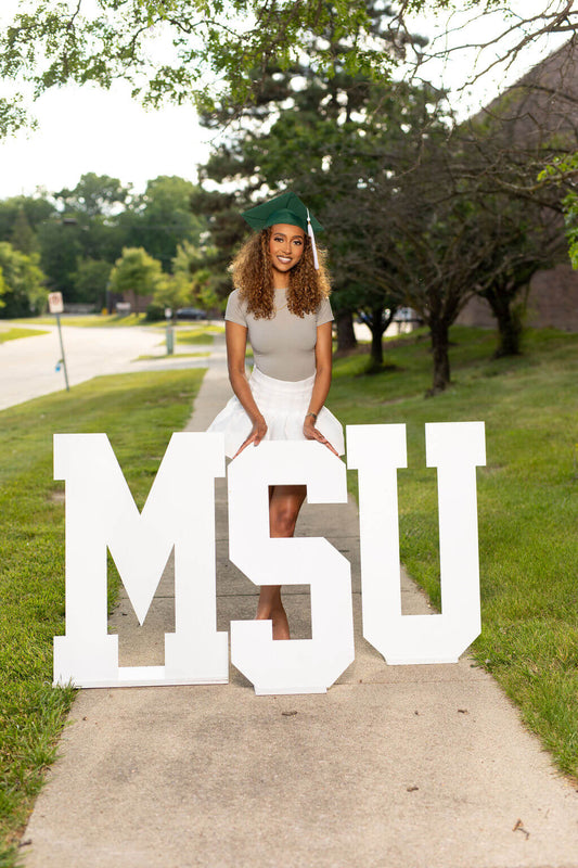 senior model posing with MSU wooden letters.