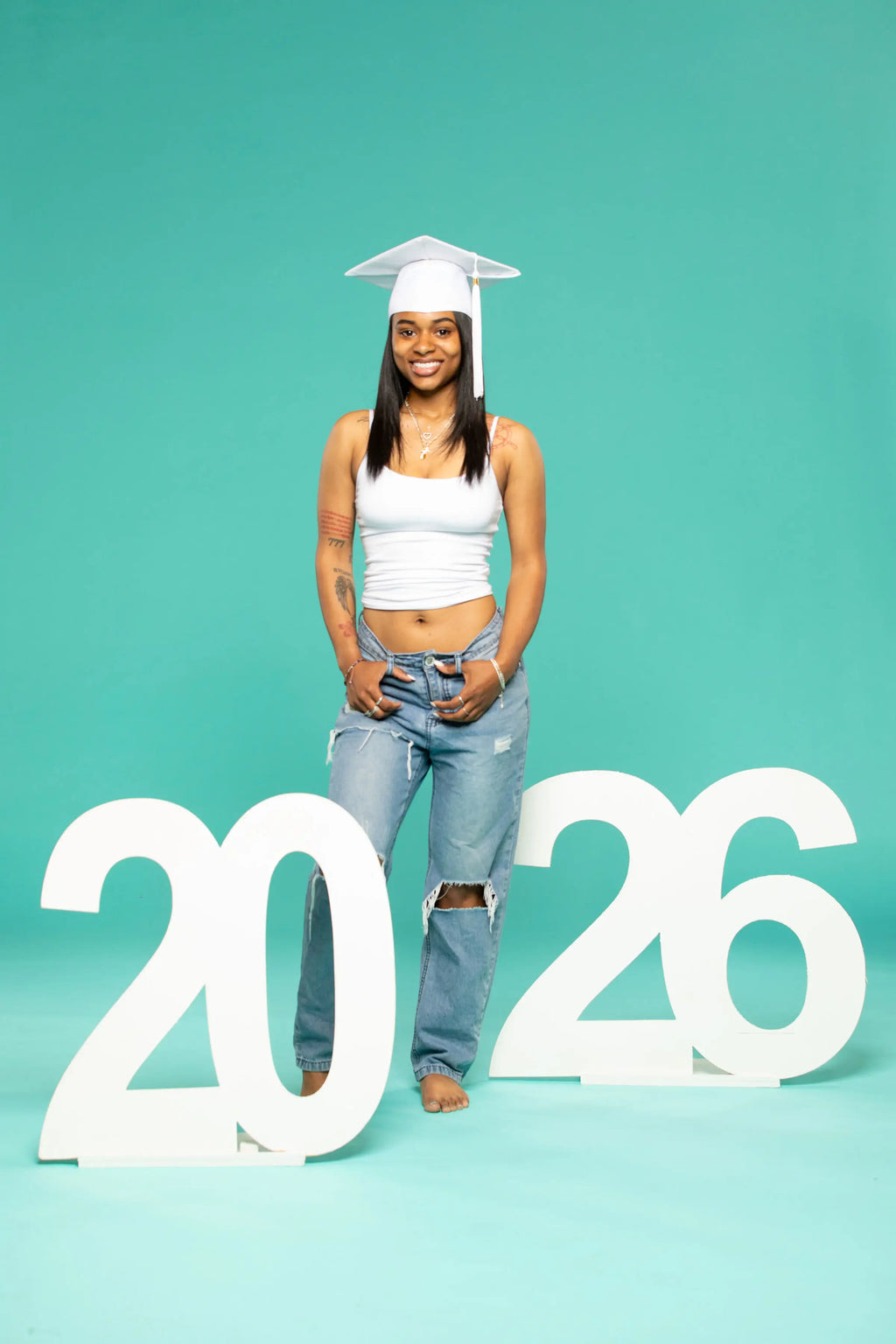 Person wearing a graduation cap with '2026' letters on a teal background