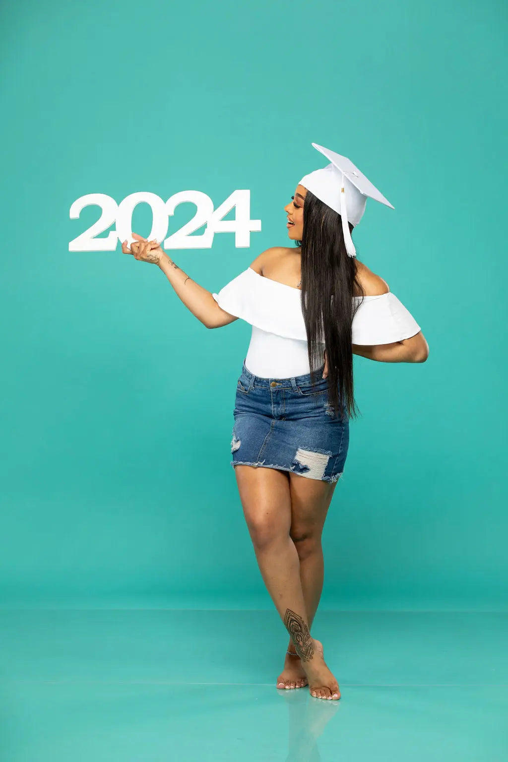 senior 2024 photo prop held by beautiful graduate looking at the 2024!