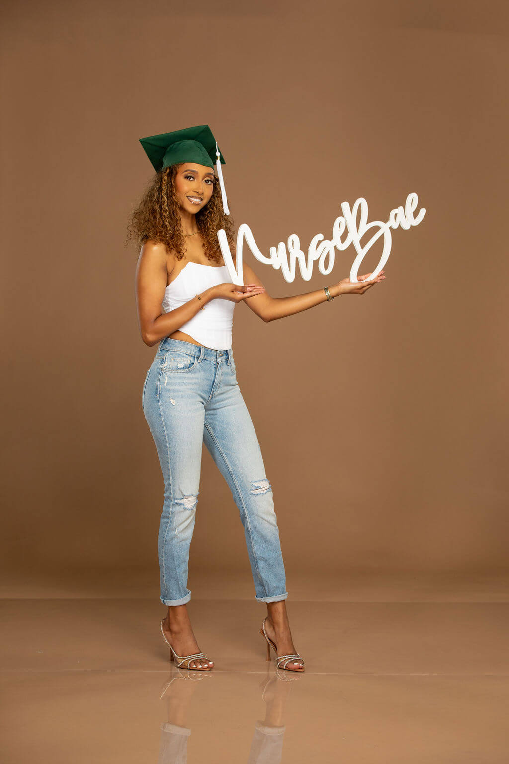 Smiling female model holding "Nurse Bae" photo prop.