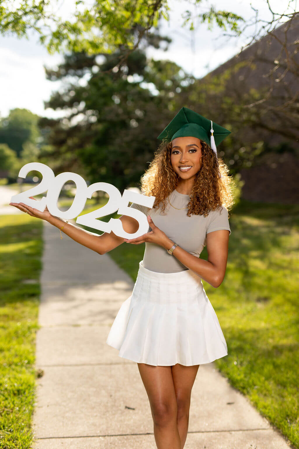model with graduation cap holding a horizontal 2025 photo prop from collageandwood.com