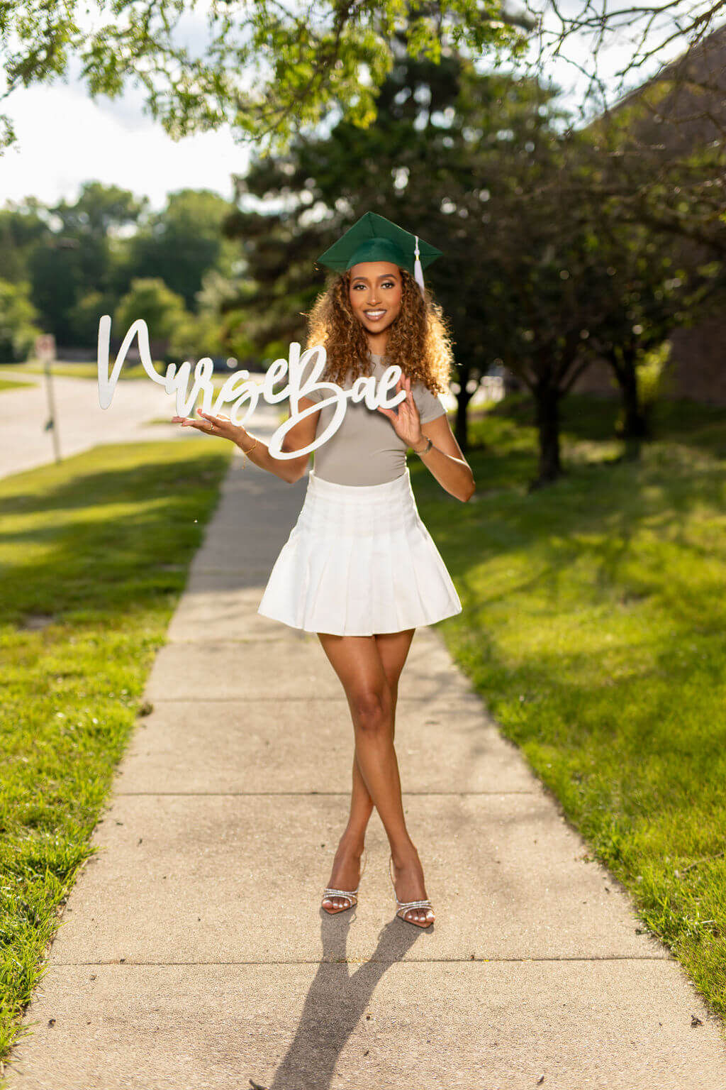 Smiling female model holding "Nurse Bae" photo prop.