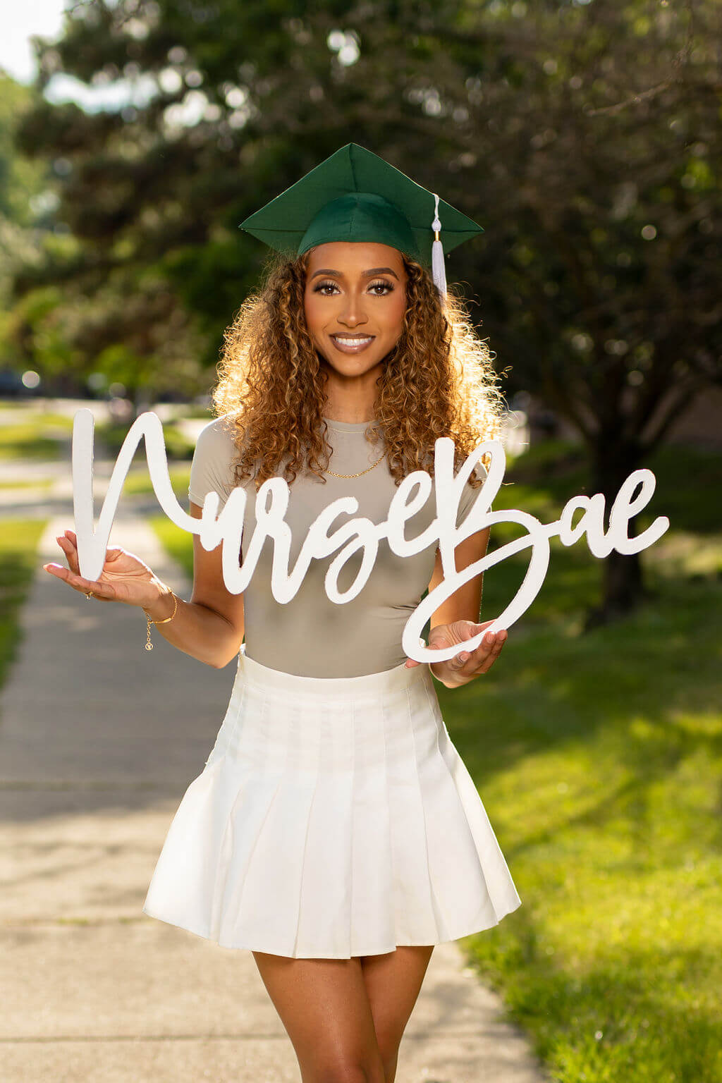 Smiling female model holding "Nurse Bae" photo prop.