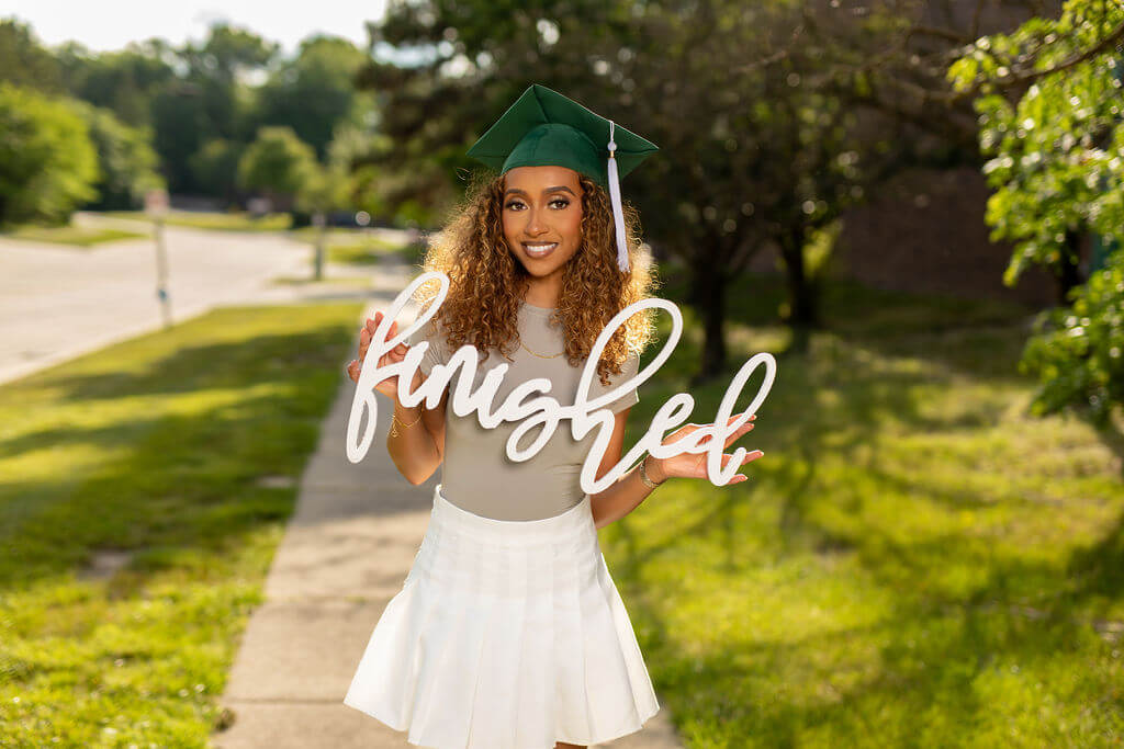 Beautiful senior model with green grad cap holding "Finished" photo prop.