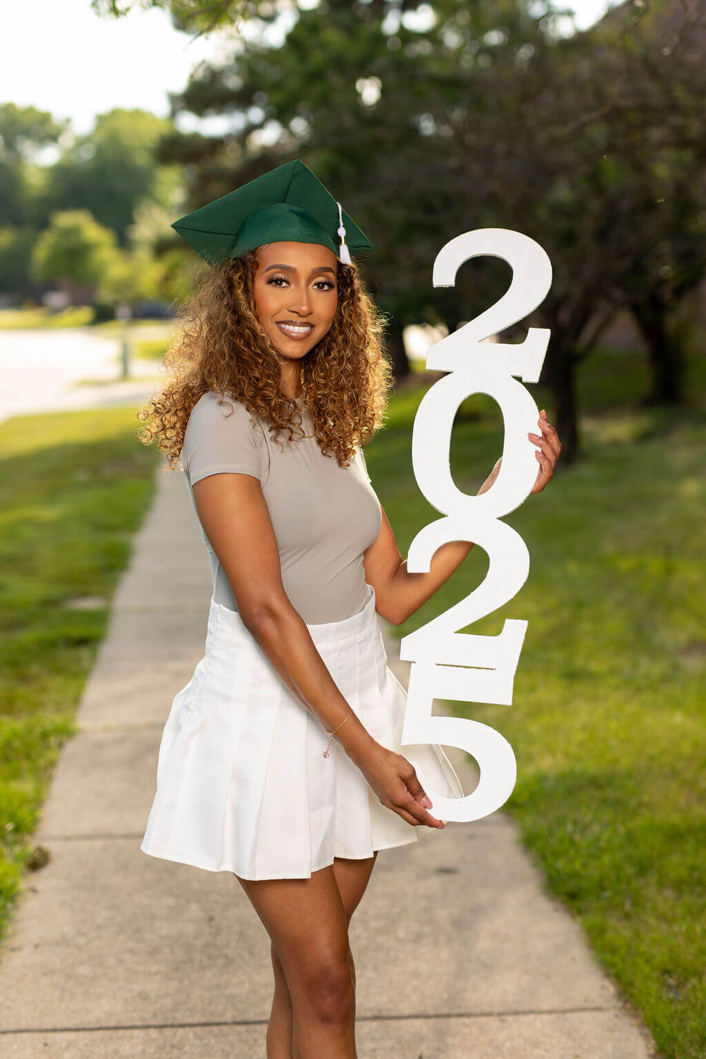 senior model in green graduation cap standing holding 2025 photo vertical prop.