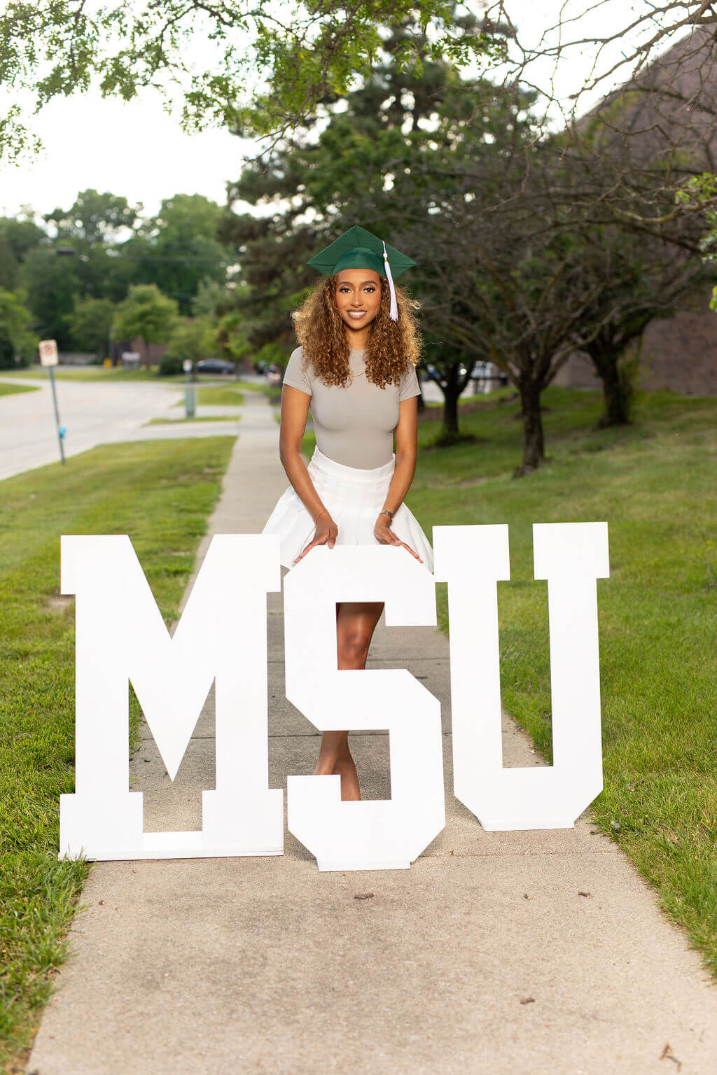 senior model posing with MSU wooden letters.