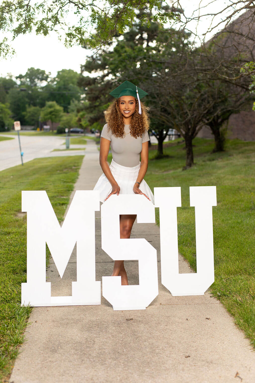 senior model posing with MSU wooden letters.