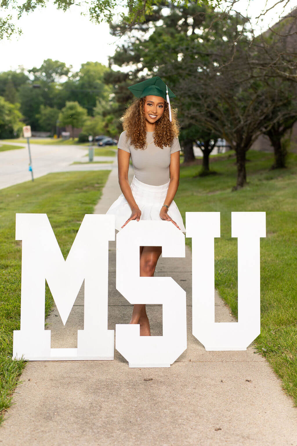 senior model posing with MSU wooden letters.