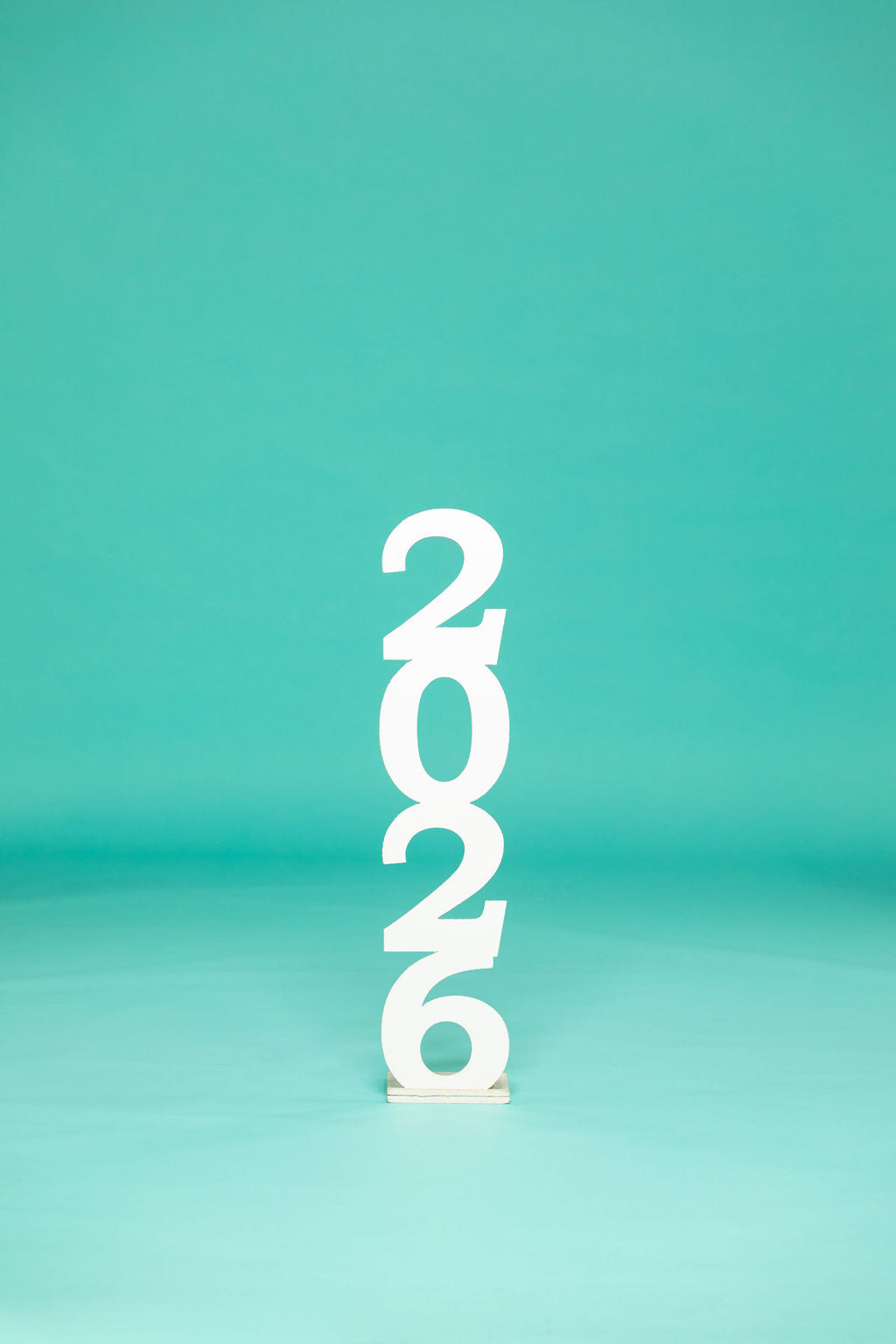 Studio display of stacked white “2026” numbers centered against a teal backdrop. 2026 senior props available now at collageandwood.com.