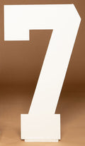 Large white freestanding numbers block '7' on a warm brown studio background. Available at collageandwood.com.