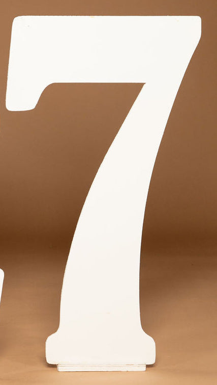 White freestanding number 7 tabletop or floor decor on a warm brown studio background.