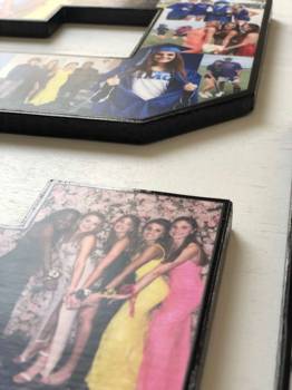 A close-up of a black-edged number frame on a light surface, showing printed photos inside. 