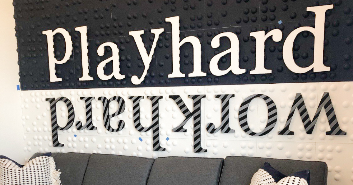 Play hard, work hard custom wall lettering above a couch.