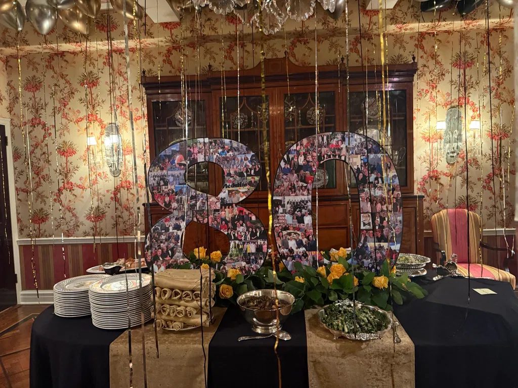 Giant 80 photo collage displayed on a buffet table with yellow roses at an 80th birthday party