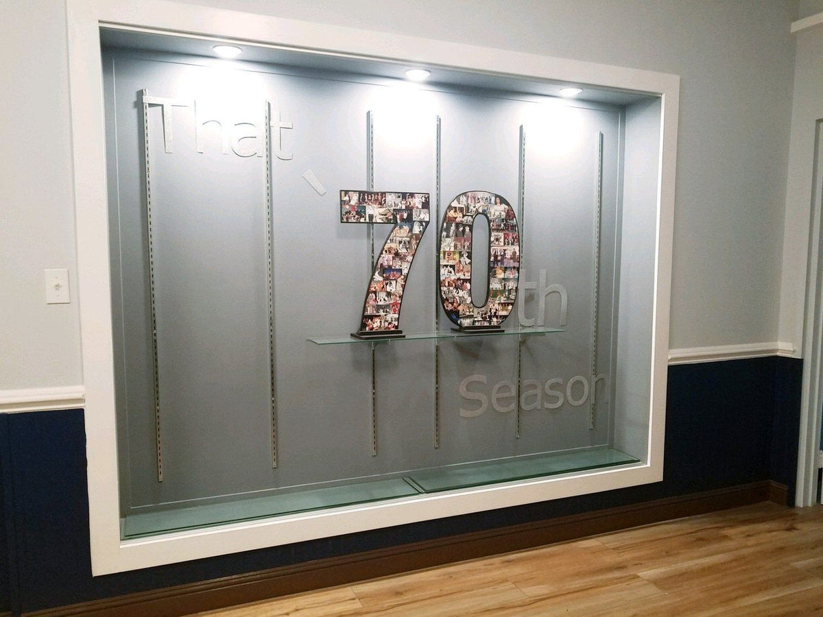 A lit display case holding a giant 70 photo collage for a 70th season celebration