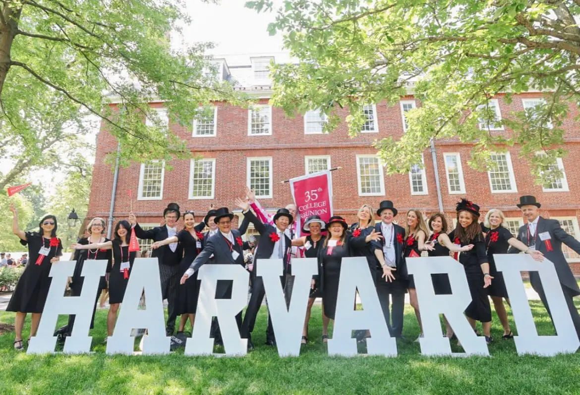 Alumni at a 35th college reunion celebrating behind giant white wooden letters