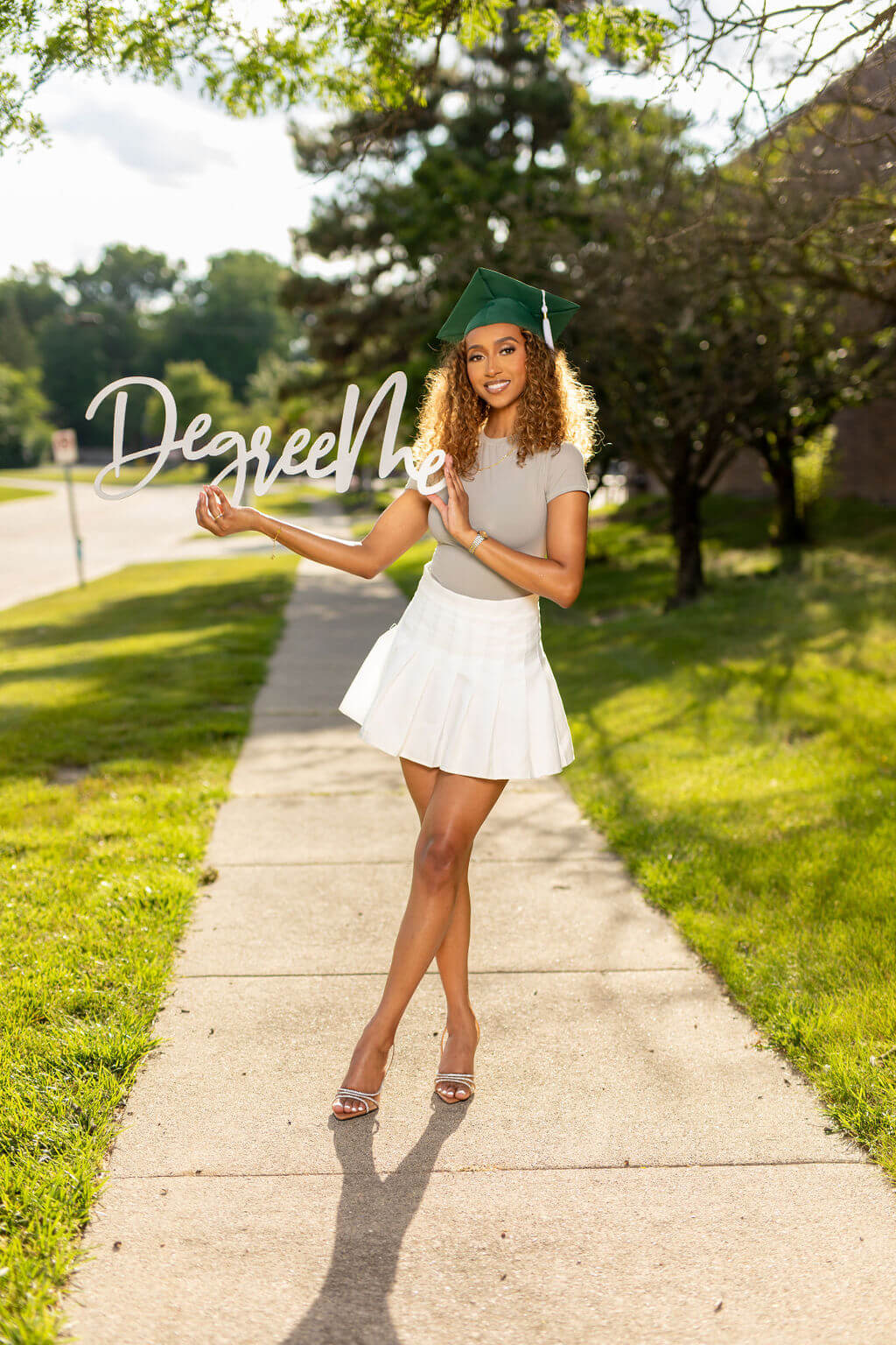 Degree Me Photo Prop, Held by senior model in grad cap outside on sidewalk.
