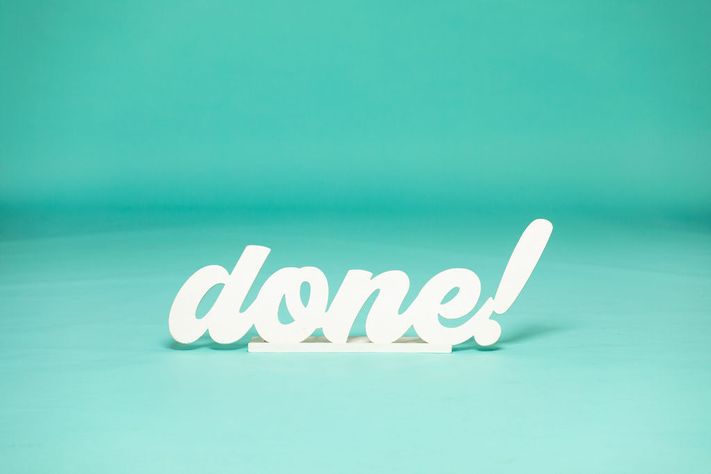 Freestanding white script word “done!” displayed on a teal background, perfect for graduation photo shoots. 2026 senior props available now at collageandwood.com.