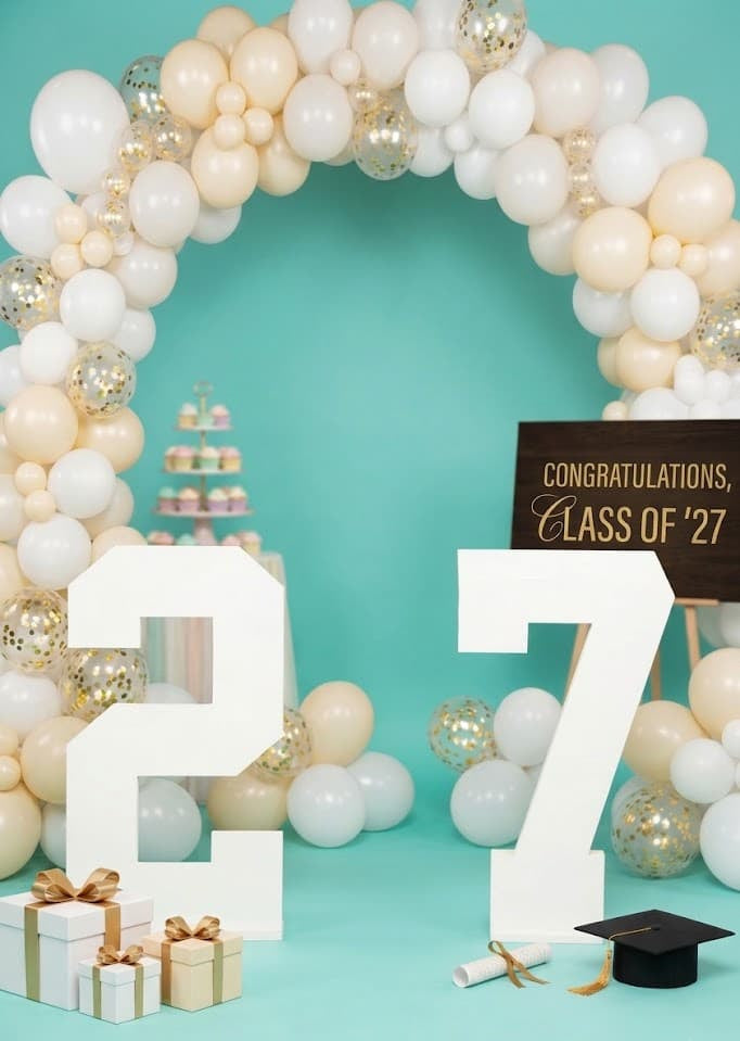 Graduation-themed decor with balloon arch, '27' numbers from collageandwood.com.