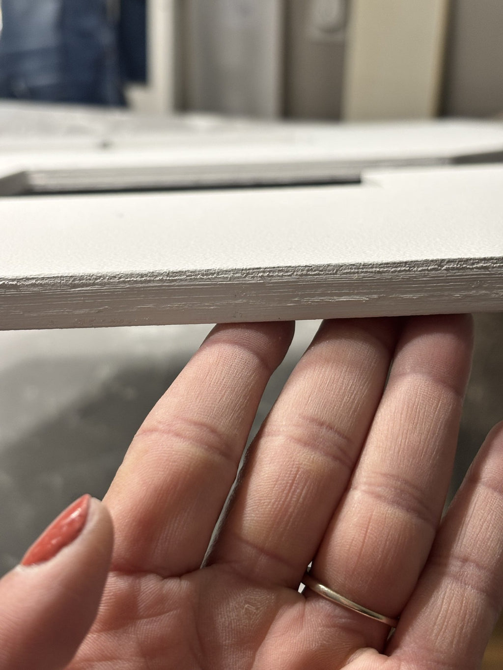 Hand holding a primed 1/2-inch plywood cutout to show its thickness