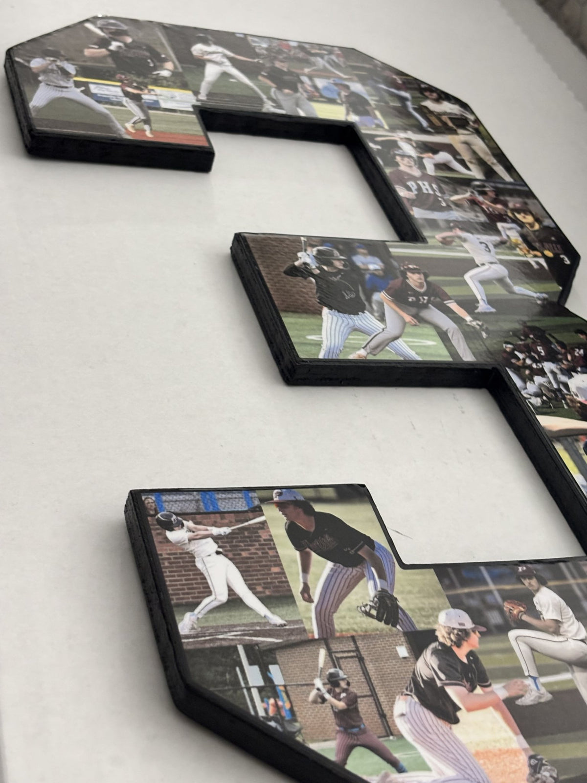 Side view of a handmade photo collage number showing the black-painted 1/2-inch plywood edge