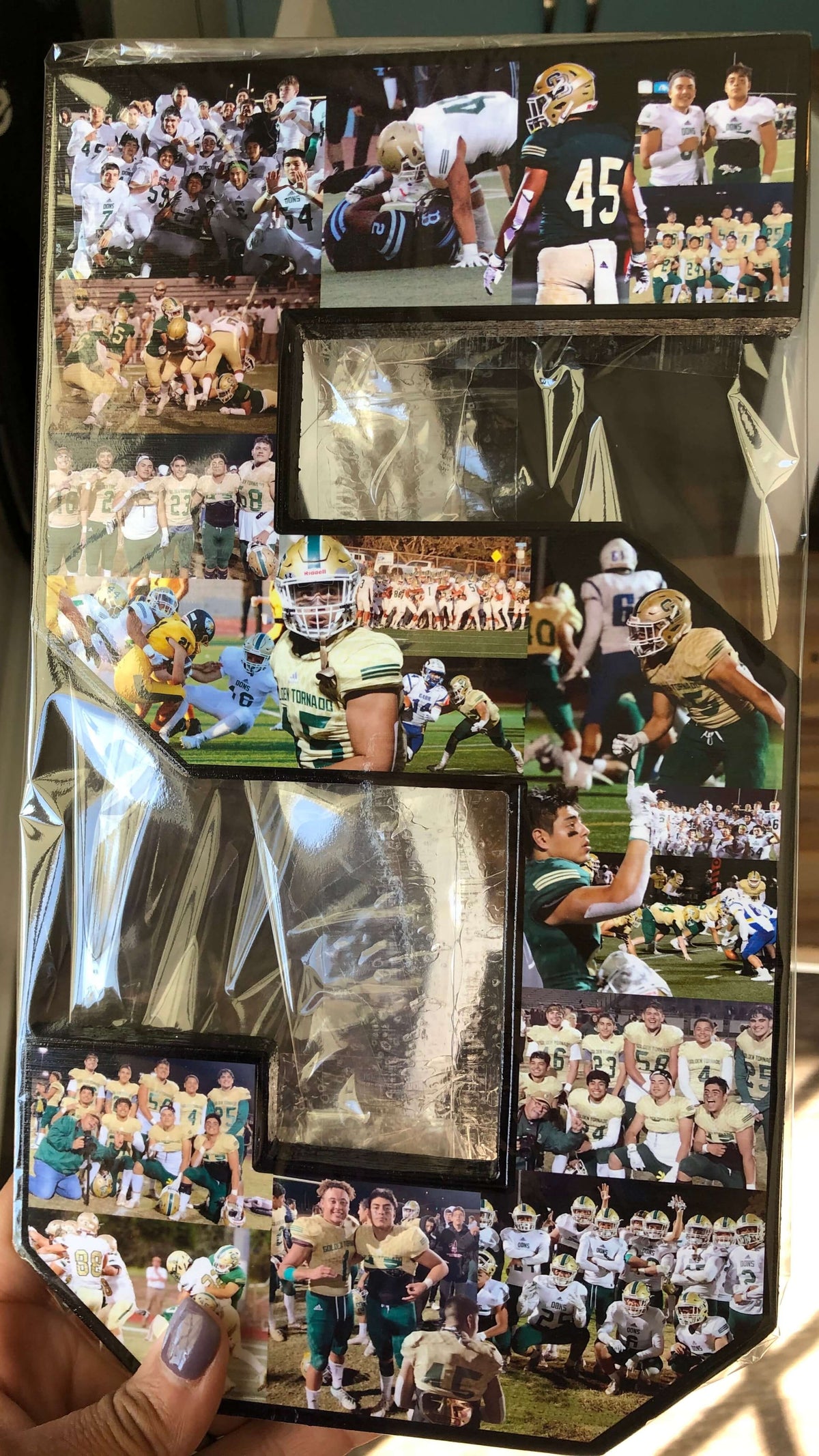 Collection of football photos wrapped in  cellophane, held by artist Crystal Waddell of CollageandWood.com