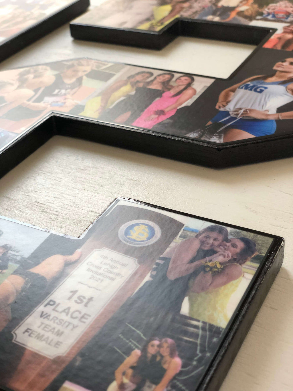 Wooden number two picture frames arranged on a light wood surface, each holding printed photos of people.