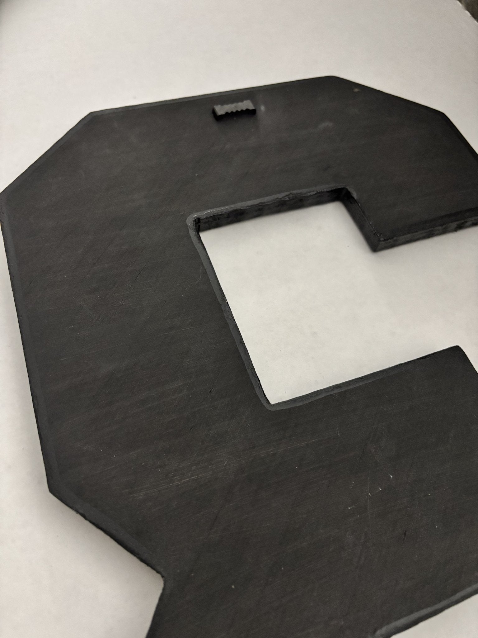 Black-painted back of a 1/2-inch plywood collage number with a sawtooth hanger, ready to hang