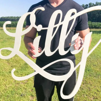 Script font Lilly name sign. Held by buff man.